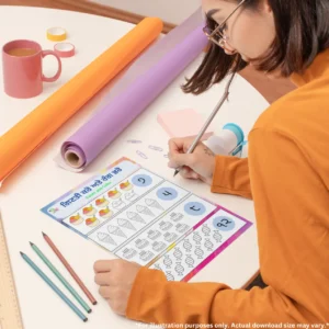 A girl wearing orange is writing on a sheet of the count and color practice book, surrounded by charts, tapes, pencils, a cup, and a sharpener.